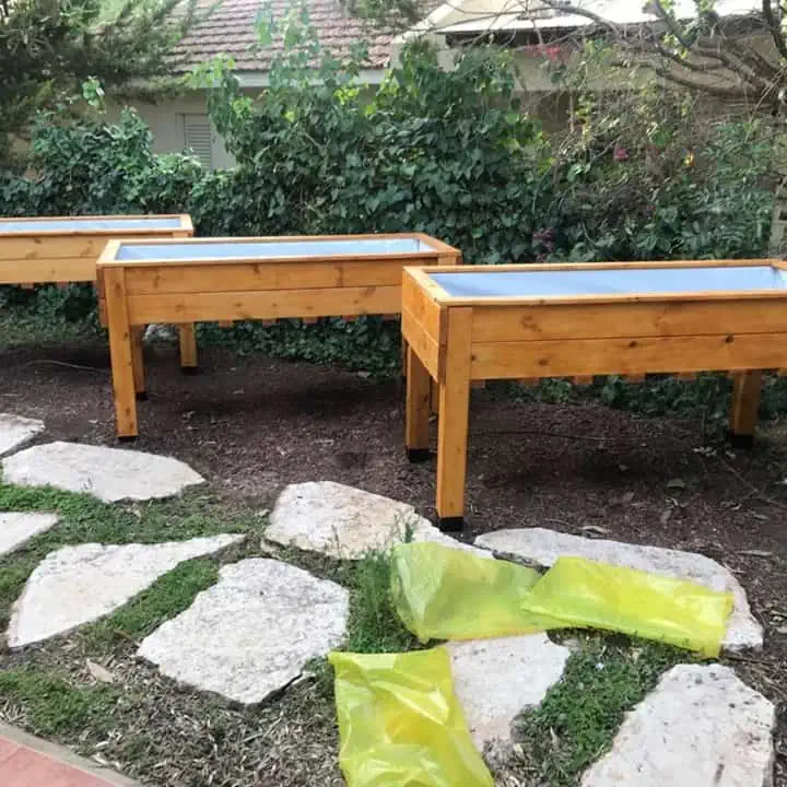 שלוש ערוגות עץ מוגבהות דגם "עדן" ריקות ניצבות בגינה לפני שתילה