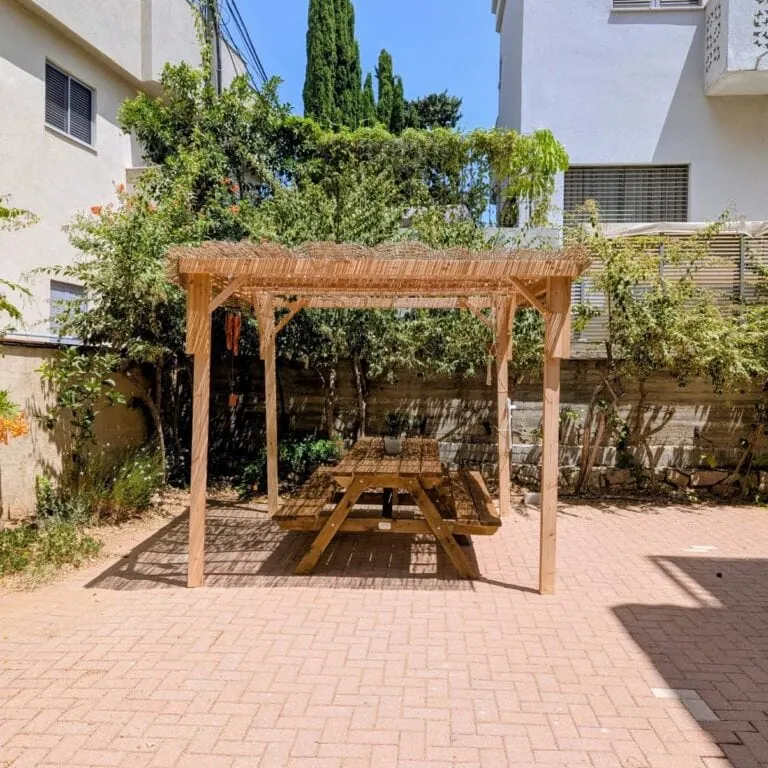 סוכה מעץ לפי מידה עם סכך וספסל פיקניק בחצר