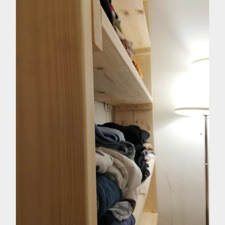 כוננית מדפים מעץ מלא דגם "שחר" עמוסה בבגדים מקופלים