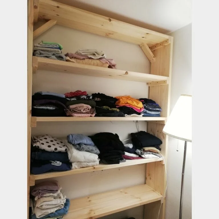 מבט מהצד על כוננית מדפים דגם "שחר" מעץ מלא מלאה בגדים מסודרים