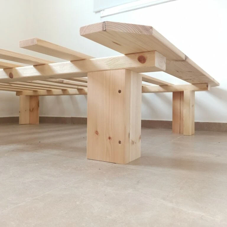 תקריב לרגל מרובעת ולמסגרת הקורות של בסיס מיטה זוגית מעץ דגם קלאסי