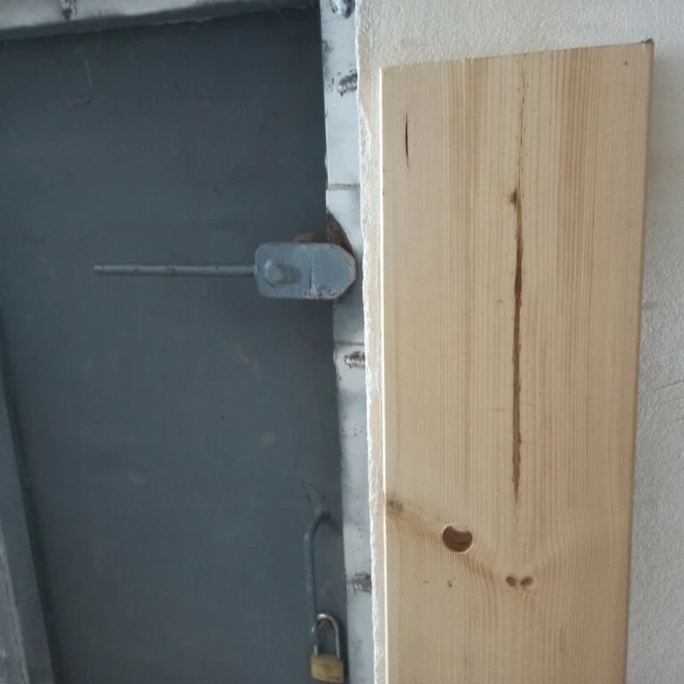 בריח הנעילה של דלת המקלט עם מנעול לצד קרש העץ עם החור