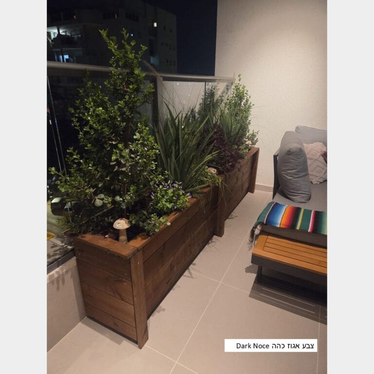 אדנית עץ ארוכה דגם "ליאת" בגוון אגוז כהה שתולה בעצים ופרחים בערב