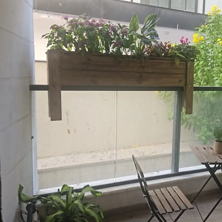 אדנית עץ למעקה דגם "אהוד" תלויה על מעקה זכוכית במרפסת