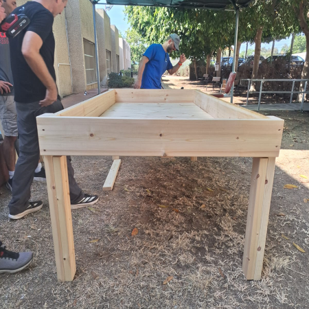 ערוגה מוגבהת מעץ דגם "ניצן" עם מסגרת עליונה ורגליים, בהרכבה בחצר